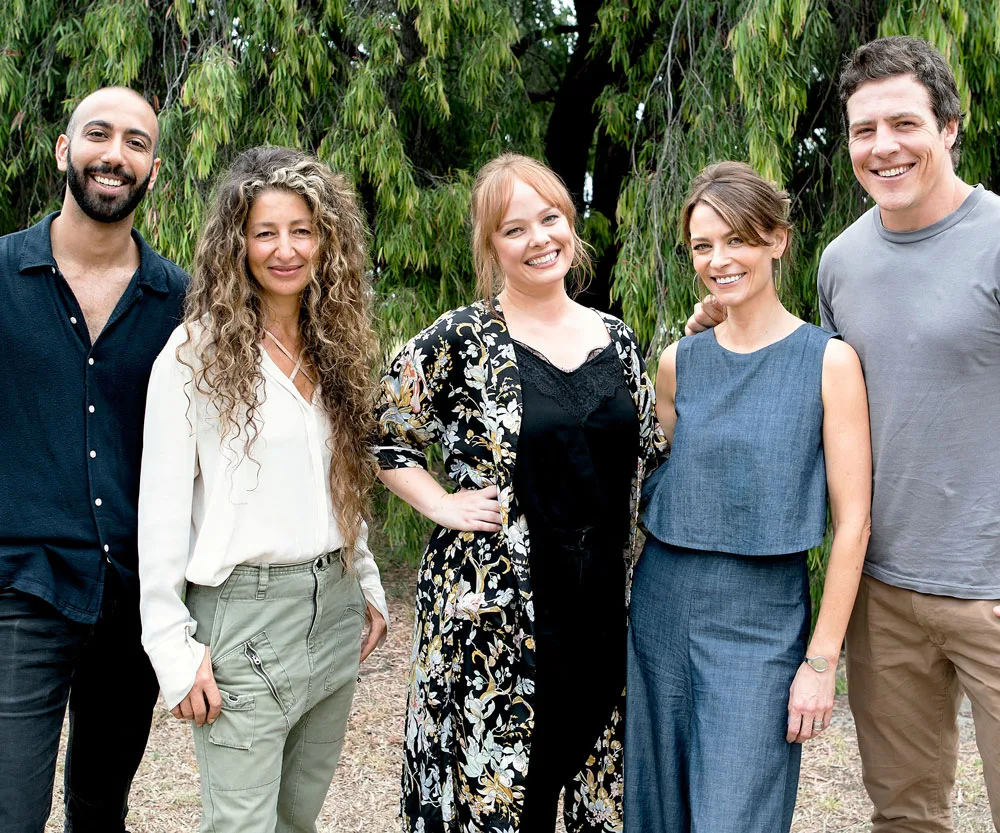 Five actors from "Five Bedrooms" smiling outdoors in casual attire.