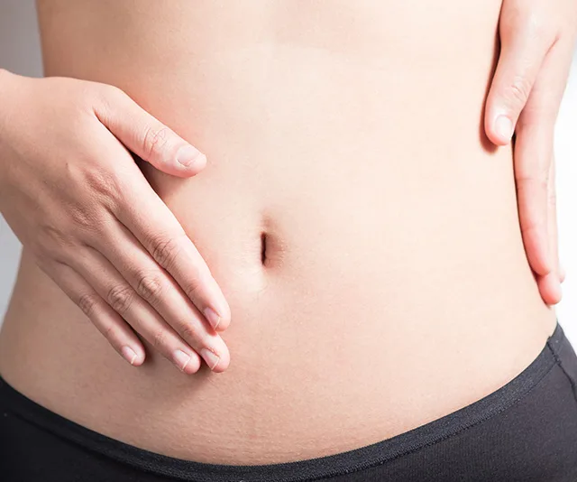 Person holding their stomach, wearing black period underwear.