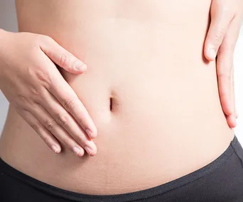 Person holding their stomach, wearing black period underwear.