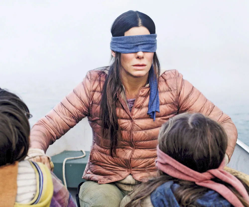 A blindfolded woman in a boat with two children, from the movie Bird Box.