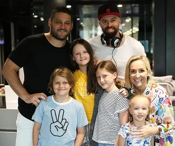 People posing together, two adults and four children smiling in a group photo.