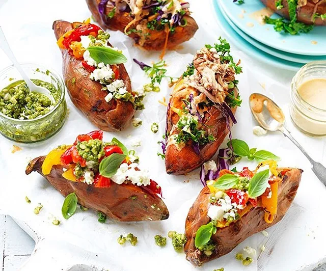 Baked sweet potatoes topped with feta, basil, red peppers, pesto, and shredded vegetables.