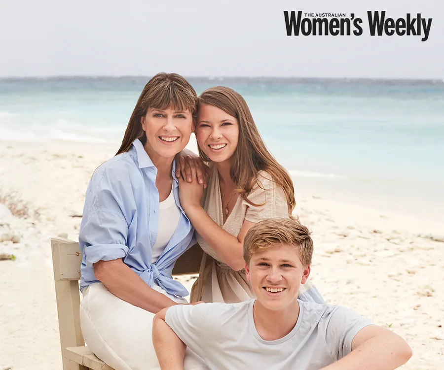Family sitting together smiling on a beach, featured in The Australian Women's Weekly magazine.
