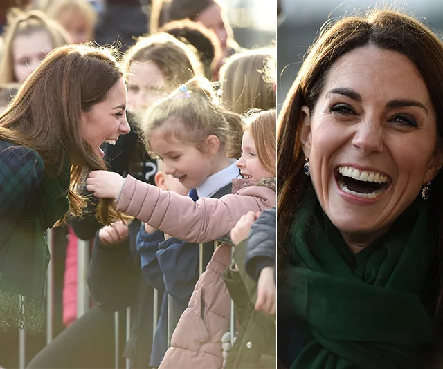 A woman smiling warmly at children who are reaching out to her, engaging in a joyful interaction.