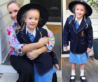 A young girl in a school uniform with braids and a wide-brimmed hat, standing and sitting with a woman.