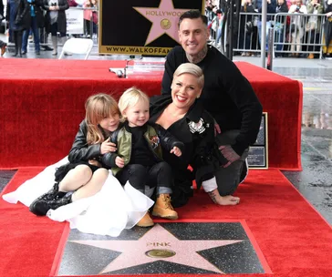Family posing with Pink's Hollywood Walk of Fame star, red carpet, and crowd in the background.