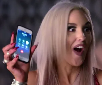 Woman with blonde hair, surprised expression, holds phone showing incoming call screen.