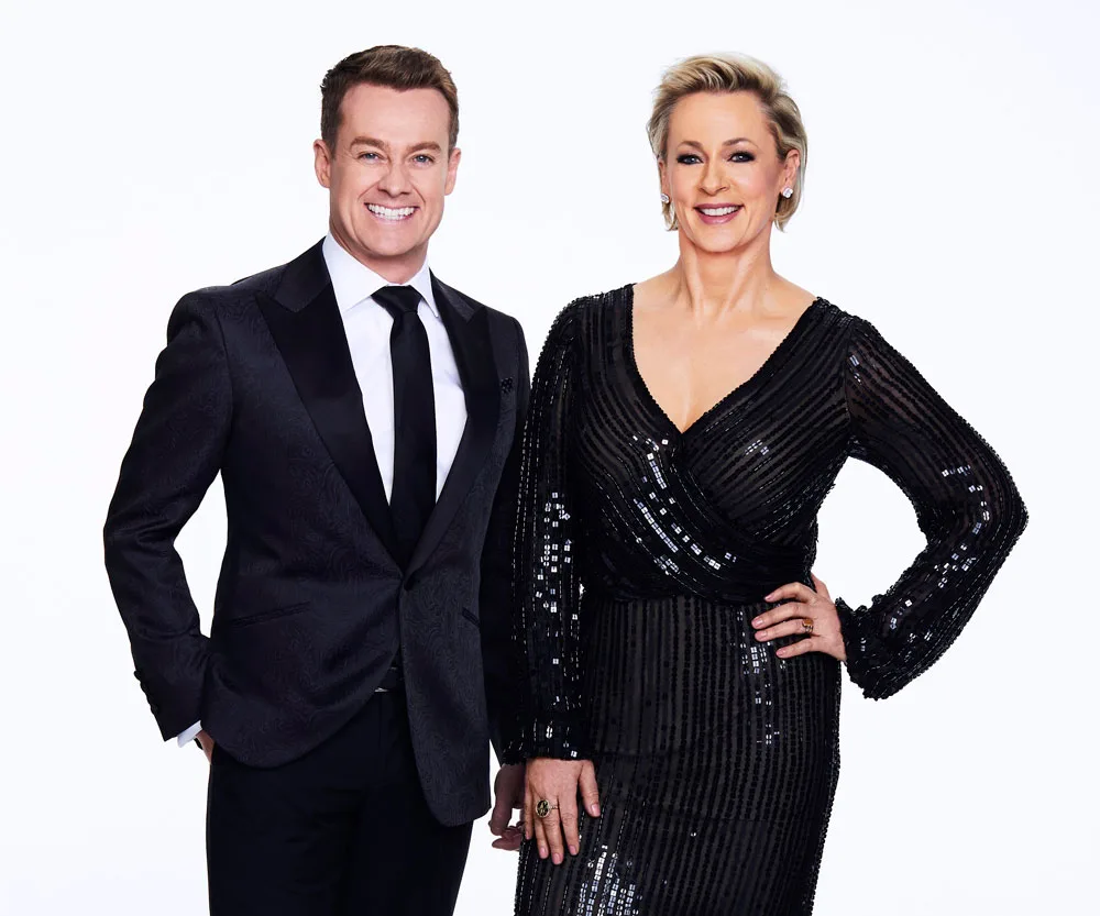 Formal duo in black attire, smiling against a plain backdrop.