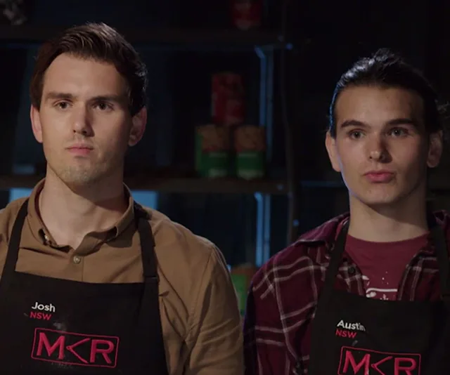 Two contestants wearing MKR aprons on a cooking show set, standing serious.