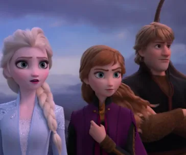 Elsa, Anna, and Kristoff from Frozen 2 stand determinedly, gazing into the distance against a cloudy backdrop.