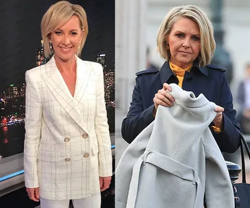 Two women with short blonde hair. One wears a white blazer, the other a navy coat holding a gray garment.