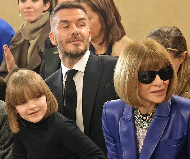 Three people at a fashion show: a girl, a man in a suit, and a woman in sunglasses and a blue jacket.