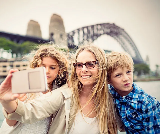 Family taking a selfie with the Sydney Harbour Bridge in the background.