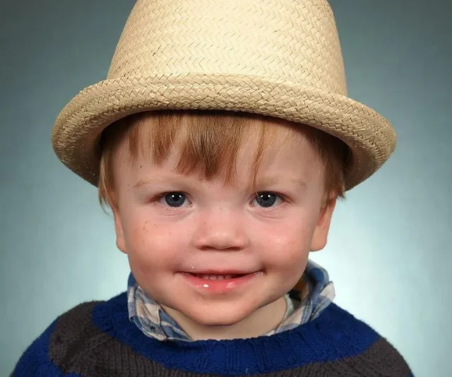 Young child wearing a straw hat, smiling at the camera.