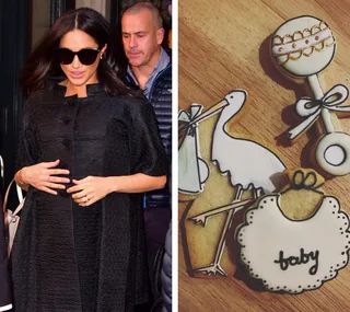 A woman in black coat with sunglasses alongside baby-themed cookies on a wooden table.