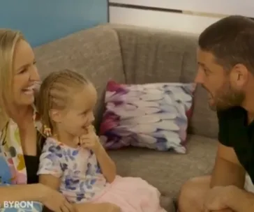 A woman, child, and man sitting on a couch, engaged in a cheerful conversation.