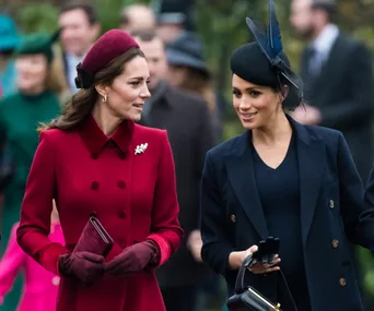 Two women in elegant outfits, one in burgundy and one in navy, walking outdoors and engaged in conversation.