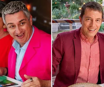 Two smiling men in vibrant jackets; left in pink, right in red, sitting at a table outdoors.