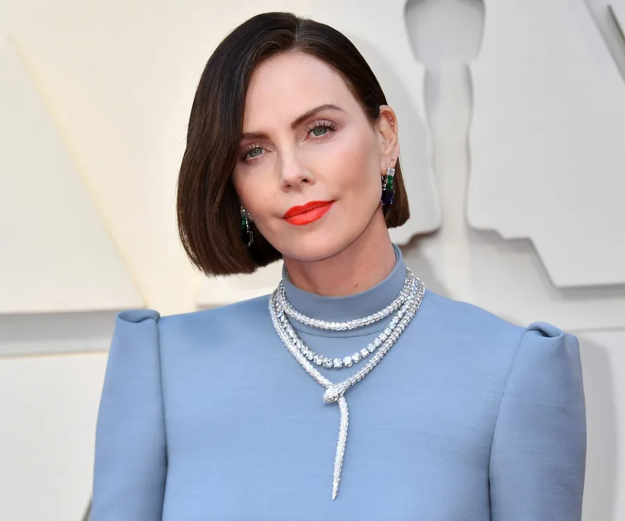 Actress in a light blue gown with bold orange lipstick and statement jewelry at the 2019 Oscars red carpet.
