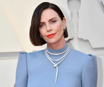 Actress in a light blue gown with bold orange lipstick and statement jewelry at the 2019 Oscars red carpet.