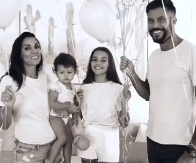 A family of four smiling, holding balloons in a festive setting.
