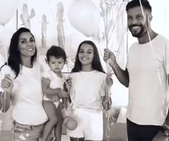A family of four smiling, holding balloons in a festive setting.
