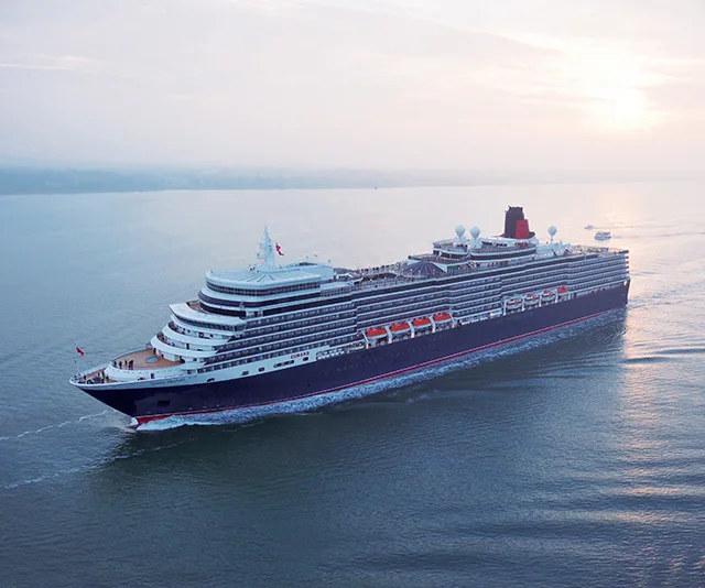Cunard cruise ship sailing at sea during sunset, viewed from above.