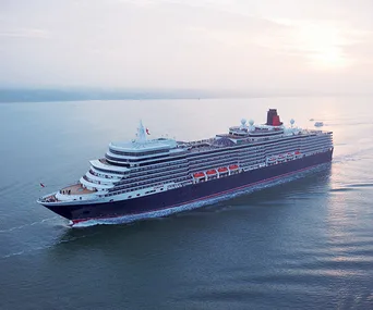 Cunard cruise ship sailing at sea during sunset, viewed from above.