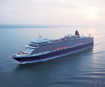 Cunard cruise ship sailing at sea during sunset, viewed from above.