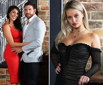 Couple posing against a brick wall on the left, woman in red dress, man in light jacket. Blonde woman in black dress on right.