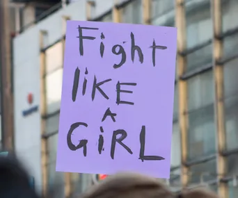 Purple protest sign with "Fight like a girl" in bold letters.