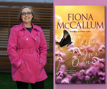 A woman in a pink coat smiles next to the cover of "A Life of Her Own" by Fiona McCallum, featuring a butterfly on flowers.