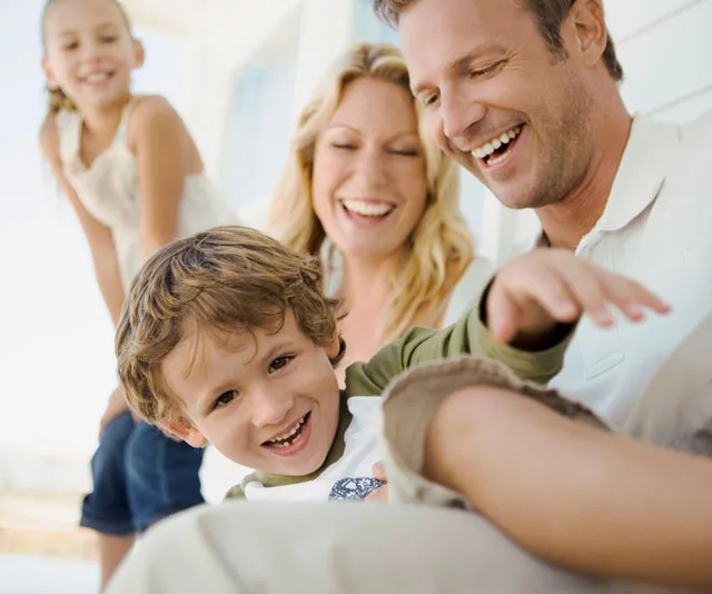 A happy family with two children, laughing and enjoying time together.