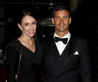 A man and woman in formal attire, smiling and posing together at an event.