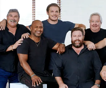 Group photo of smiling men in casual attire from "The All New Monty" cast.
