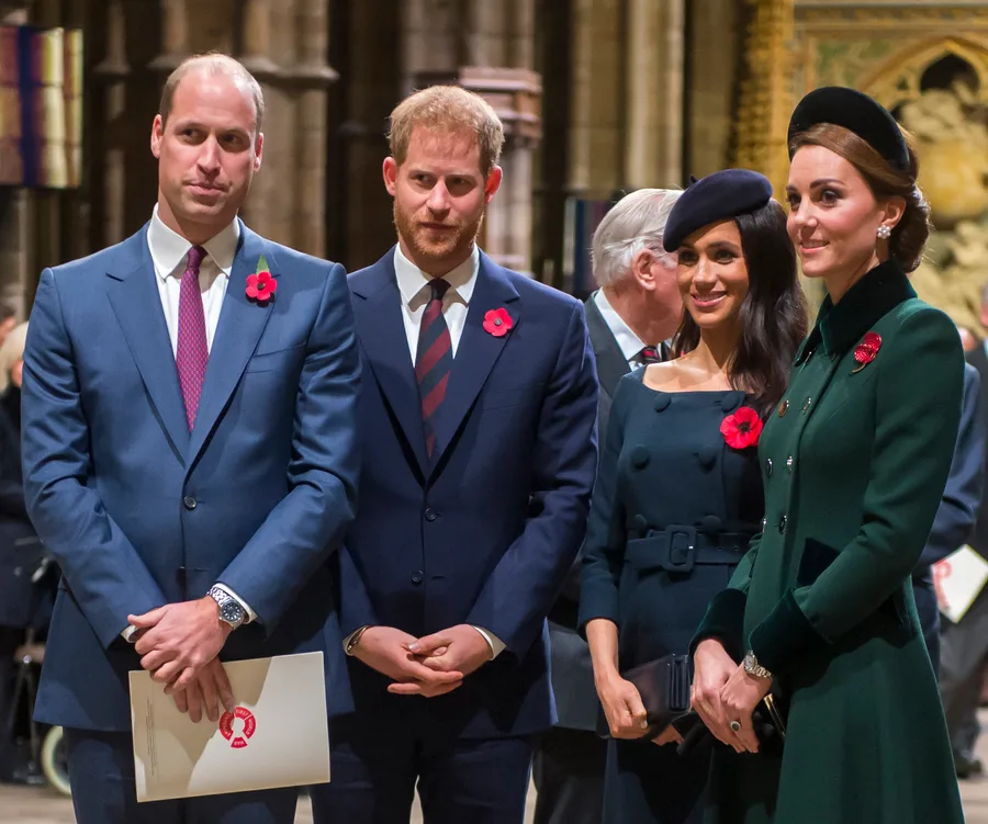 A group of people in formal attire with red poppy pins, likely attending a commemorative event.