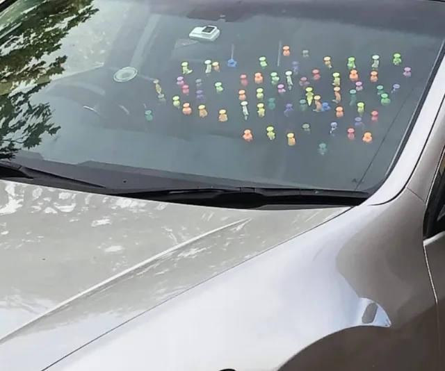 A car dashboard filled with colorful figurines lined up in rows under the windshield.