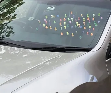 A car dashboard filled with colorful figurines lined up in rows under the windshield.