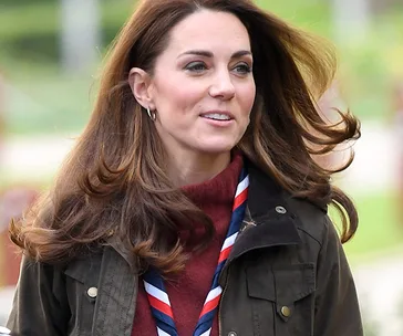 Woman wearing a Scout scarf and jacket, outdoors with a blurred green background.