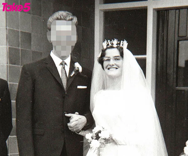 Vintage wedding photo of a smiling bride in a veil holding a groom's arm with his face pixelated.