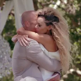 A couple embraces outdoors in a romantic setting during a wedding ceremony.