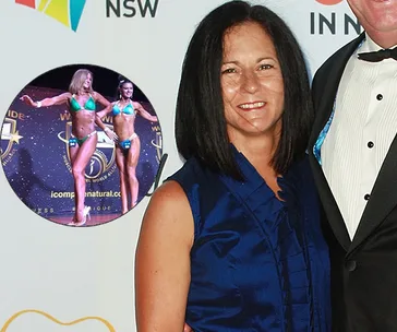 Woman in blue dress smiles beside a suited person, with inset of two female bodybuilders in green bikinis on stage.