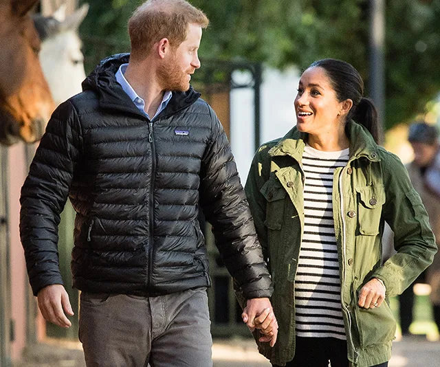 Couple walking outdoors, smiling and holding hands, both wearing jackets.