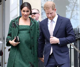I don't know who these people are, but a woman in a green coat and a man in a suit are walking down steps together.