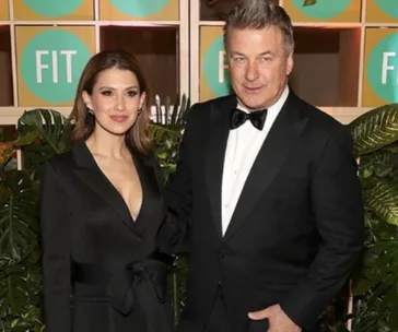 Two people in formal attire pose in front of a backdrop with "FIT" logos and greenery.