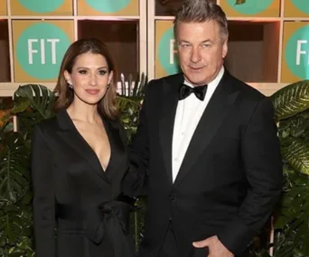 Two people in formal attire pose in front of a backdrop with "FIT" logos and greenery.
