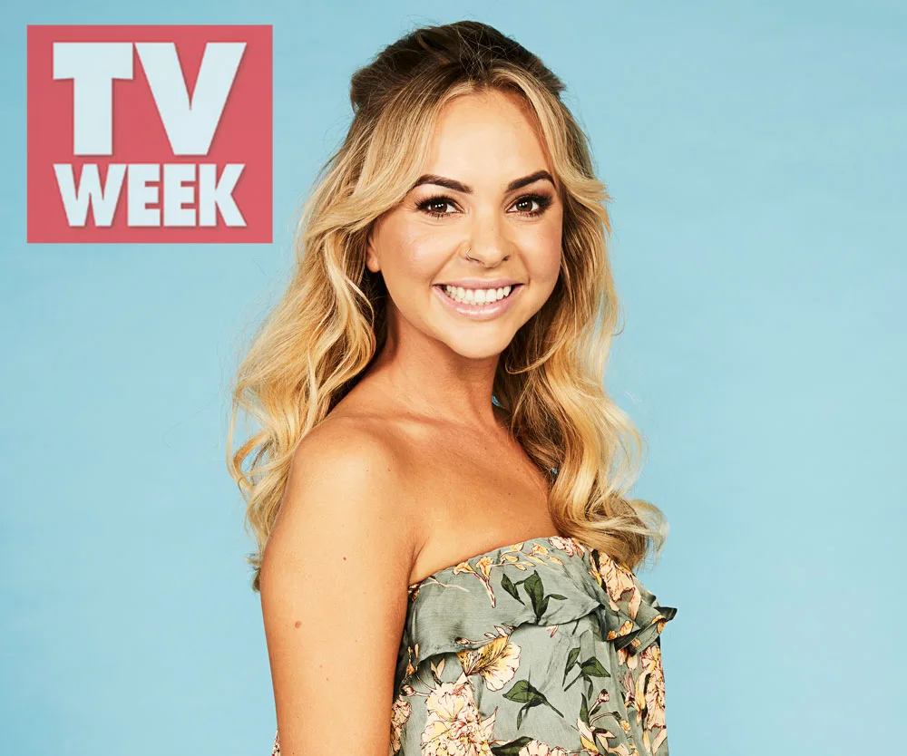 ```plaintext
Woman smiling in floral dress with TV Week logo on a light blue background.
```