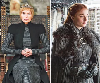 Two women in medieval outfits, one seated on a throne, wearing a crown; the other standing with fur shawl in snowy scenery.