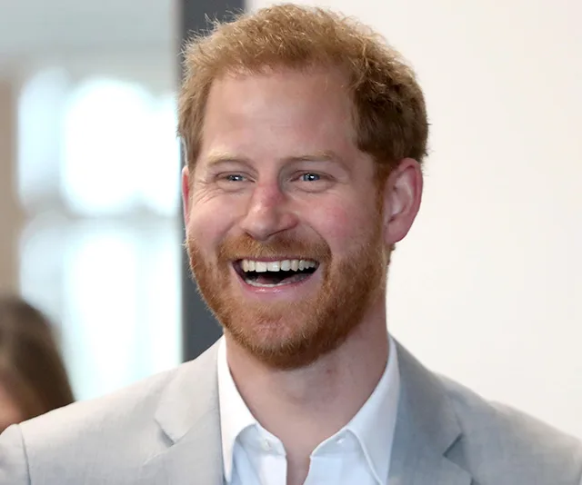 A man with red hair and beard smiling broadly, wearing a light gray suit jacket.