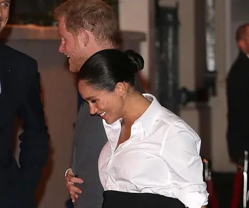 Two people smiling and interacting at an event, one wearing a white shirt and the other with a suit.